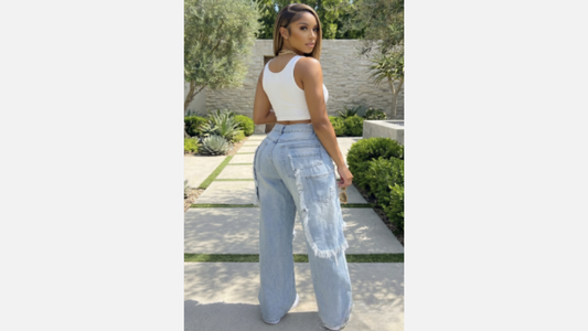 Woman wearing light blue jeans and a white top outdoors.