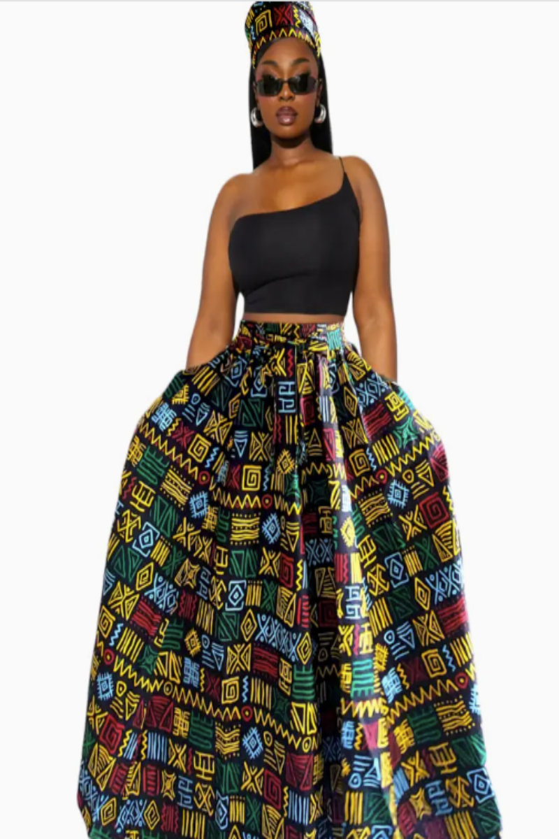 Woman wearing a black top and colorful patterned skirt with a headscarf on a white background