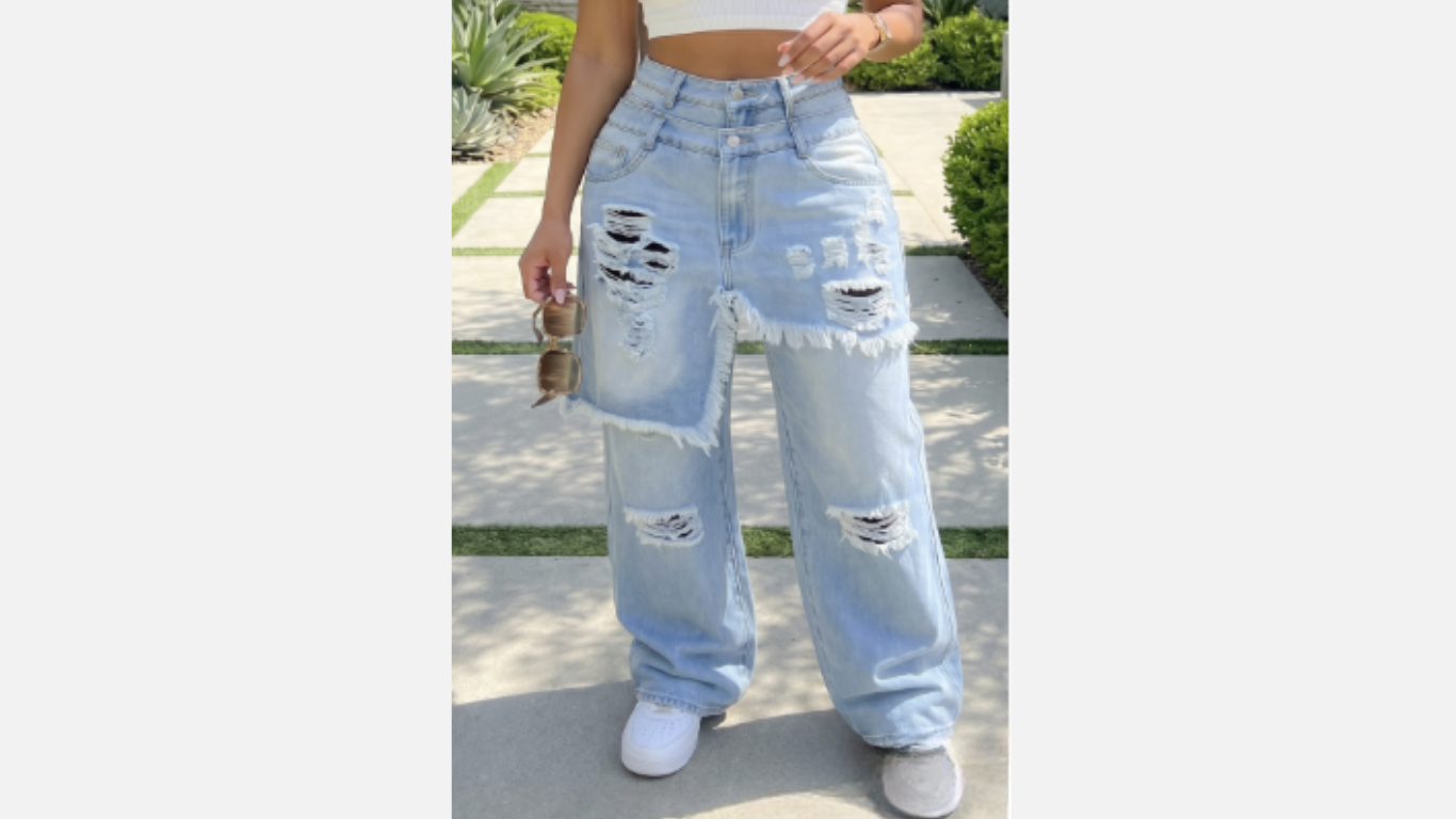 Person wearing light blue ripped jeans and white sneakers on a blurred outdoor background