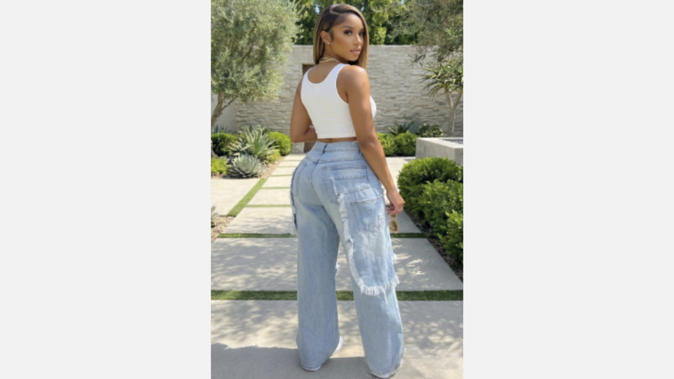 Woman wearing light blue jeans and a white top outdoors.