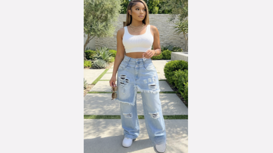 Woman wearing a white crop top and light blue jeans standing outdoors.