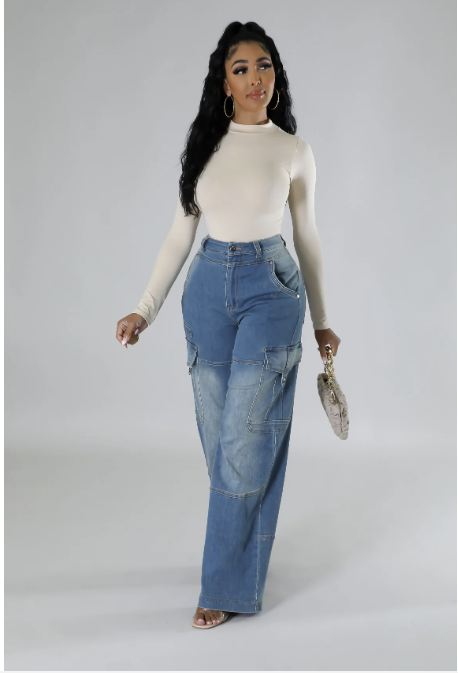 Model wearing high-waisted blue wide-leg jeans with cargo pockets, panel stitching, and a fitted beige long-sleeve top.