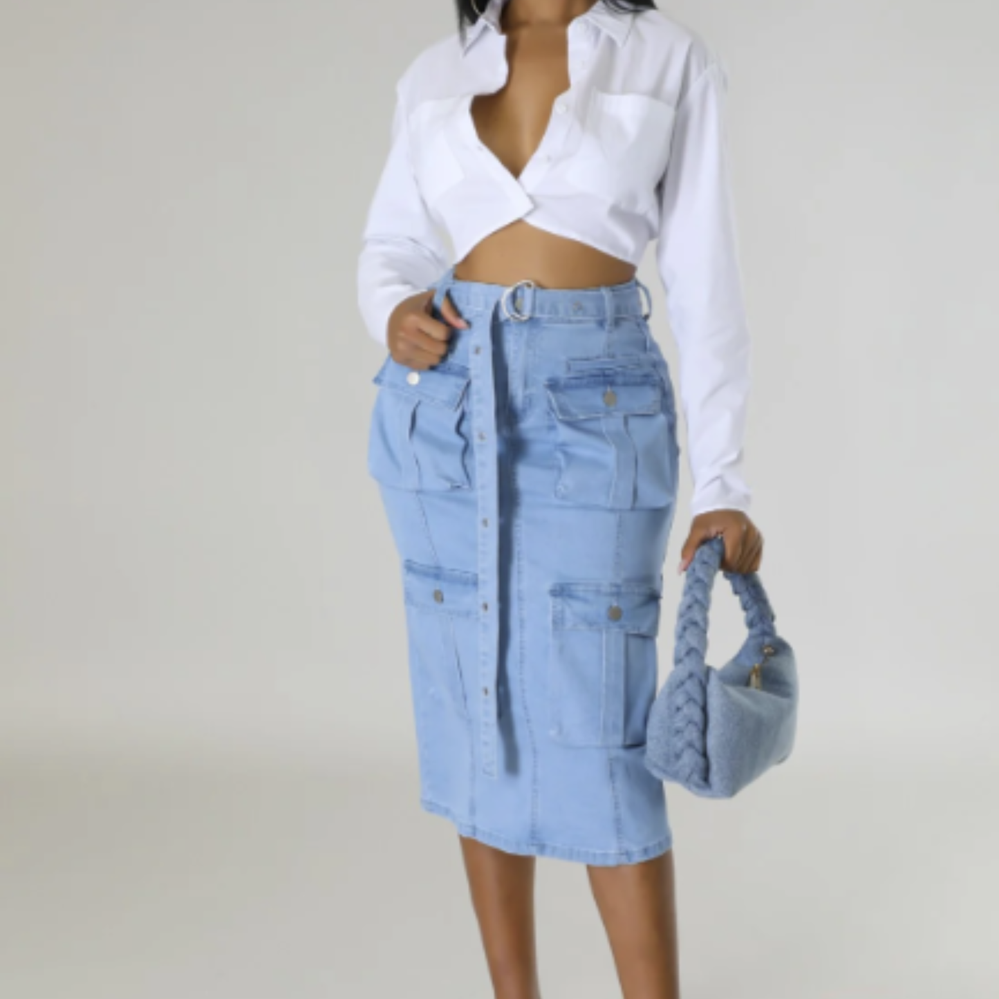 Person wearing a light blue denim skirt and white shirt on a plain background