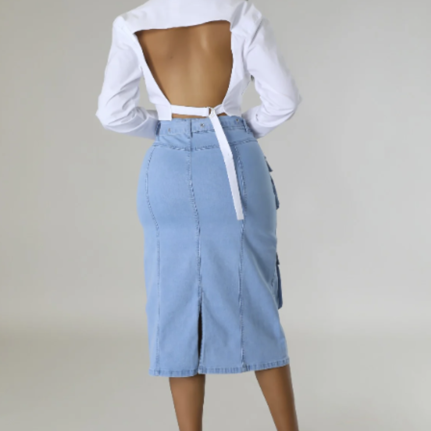 Light blue denim skirt worn with a white open-back top on a plain background